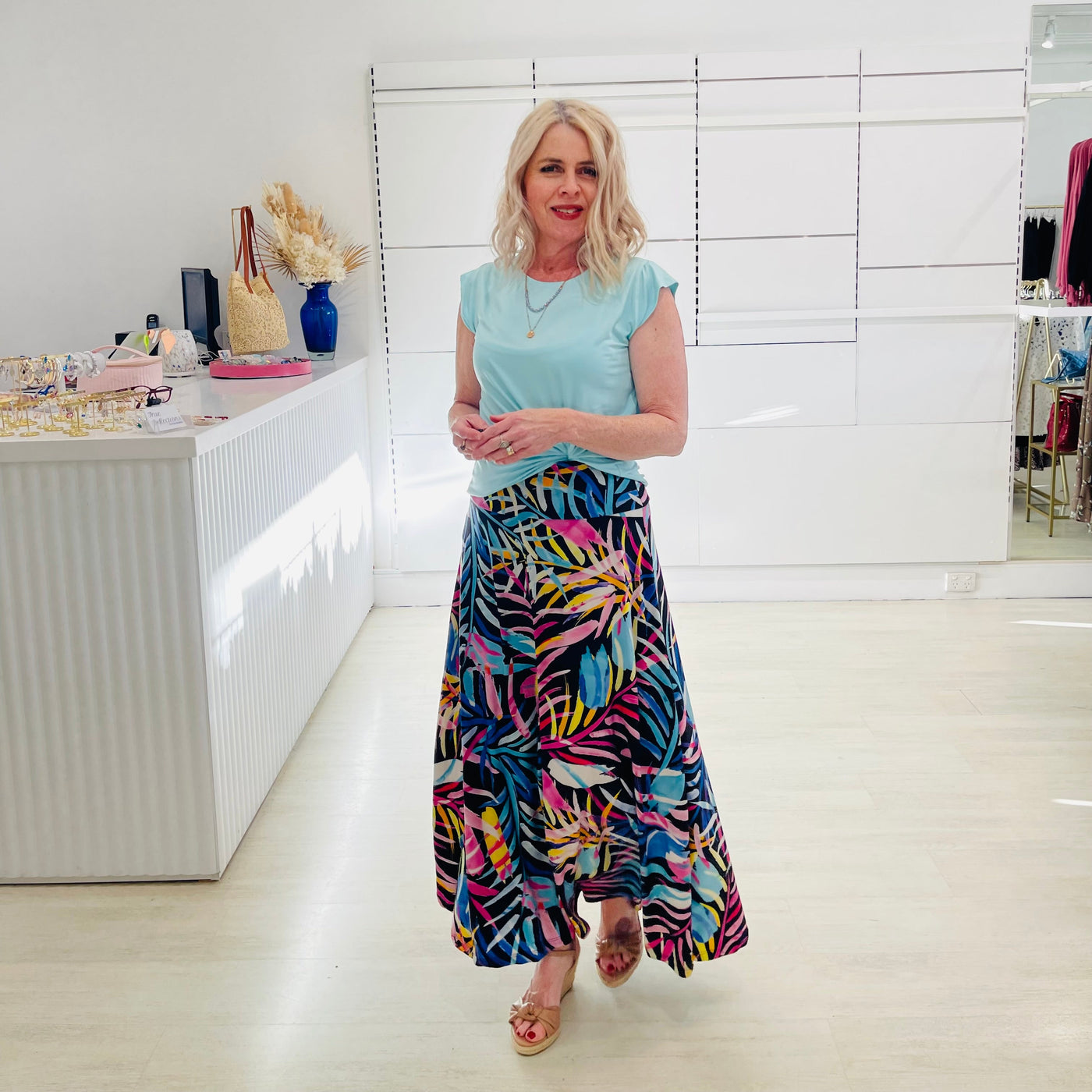 Woman wearing green t shirt with long black & floral skirt. 