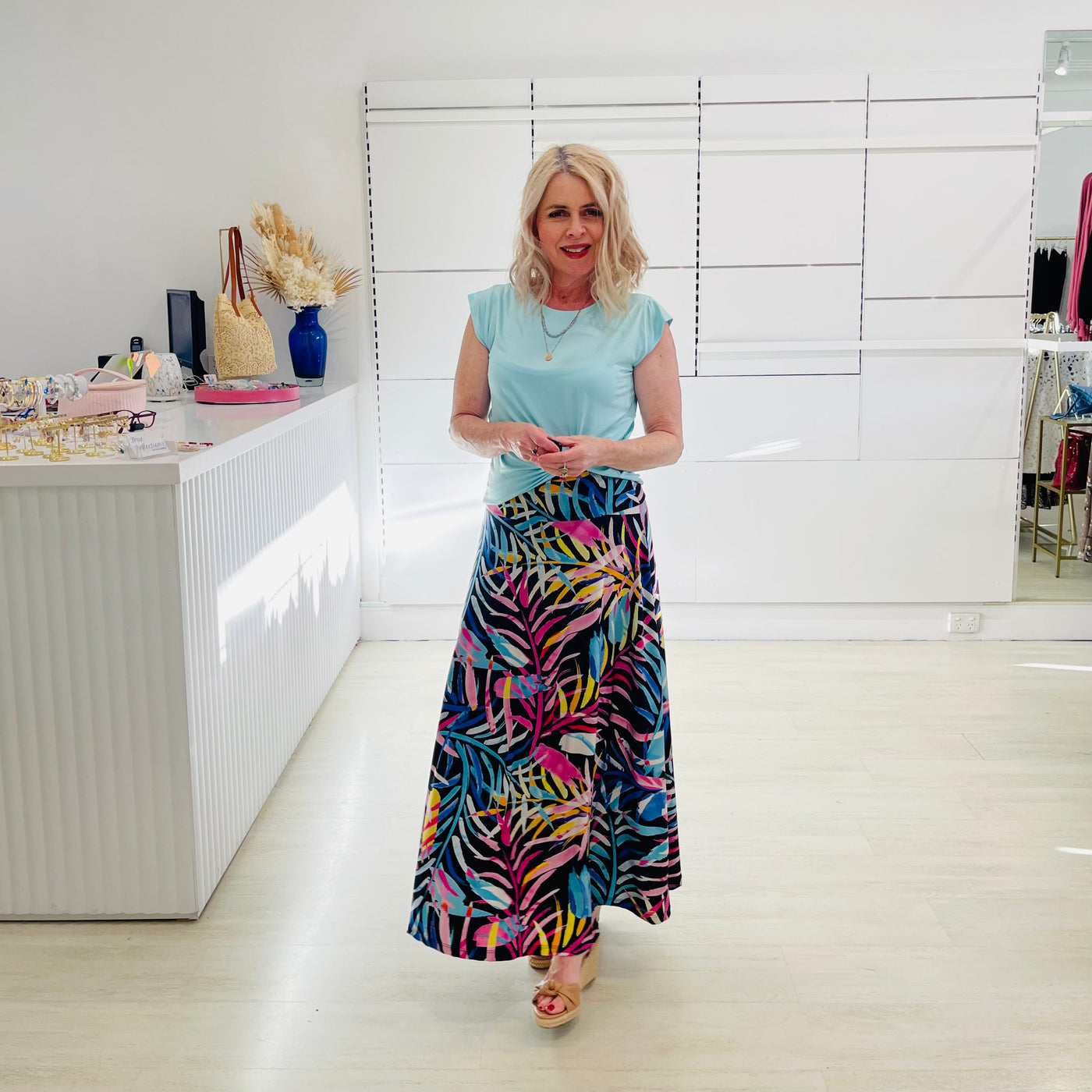 Woman wearing green t shirt with long black & floral print skirt. 