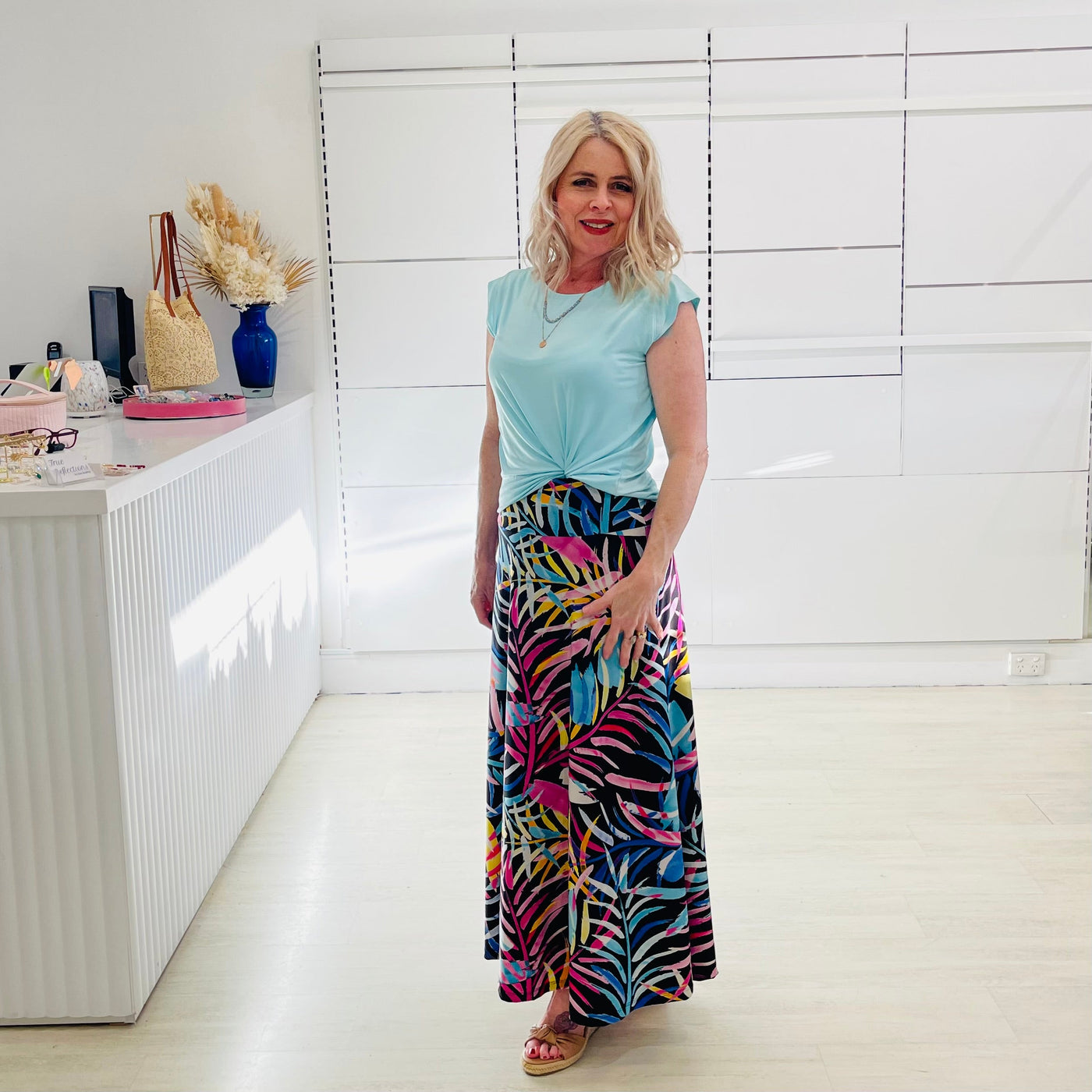 Woman wearing green t shirt with long floral skirt. 