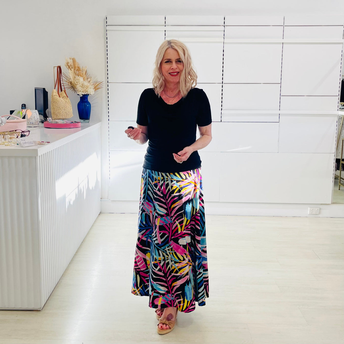 Woman wearing black dressy top  with long floral skirt. 