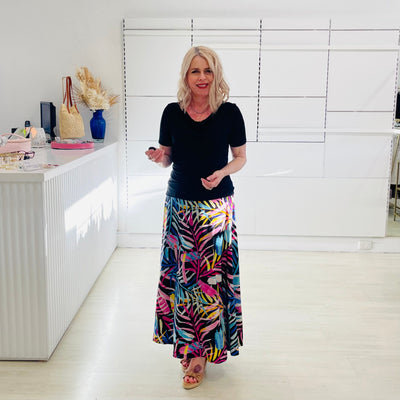 Woman wearing black dressy top  with long floral skirt. 