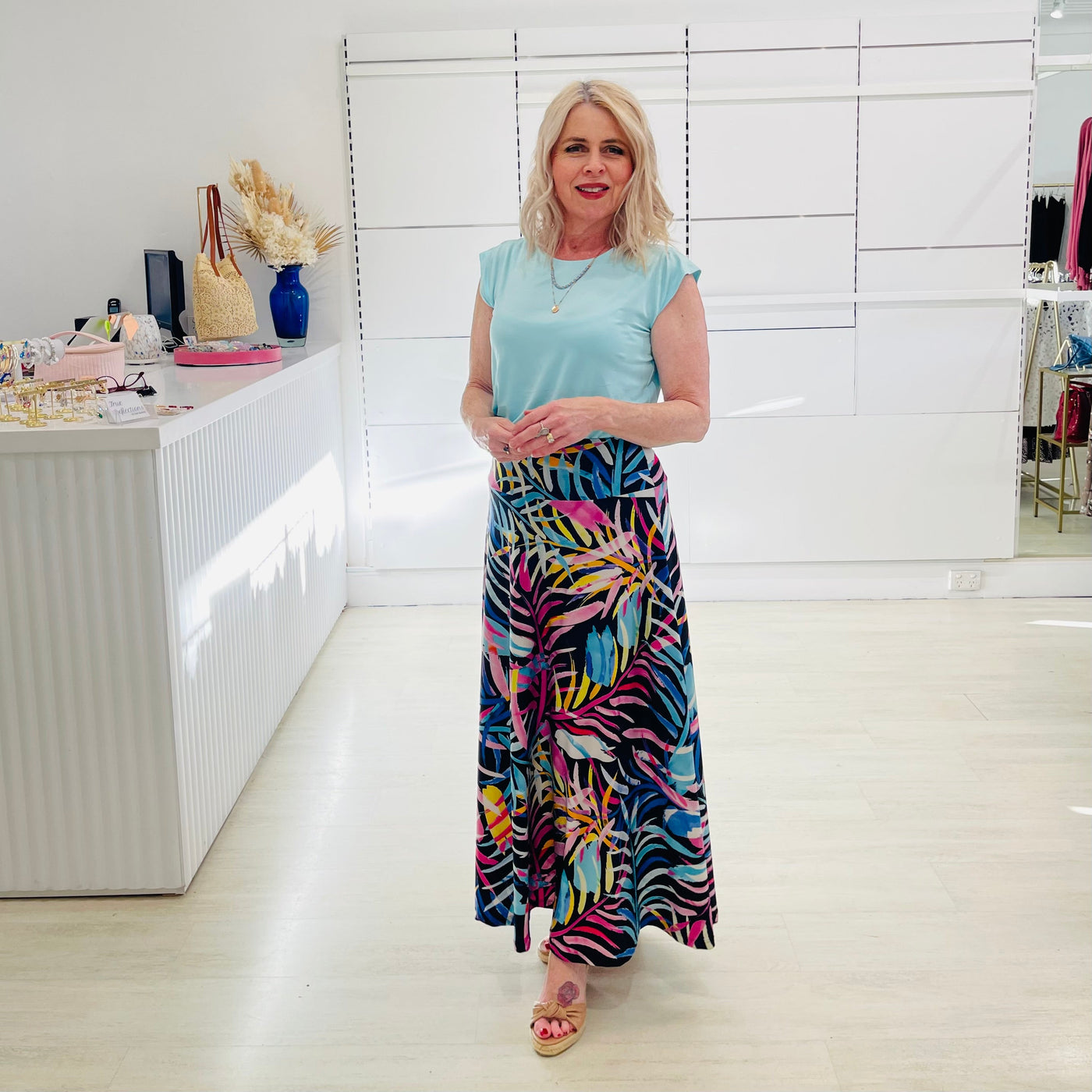 Woman wearing blue t shirt with long floral print skirt. 