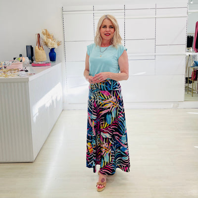 Woman wearing blue t shirt with long floral print skirt. 