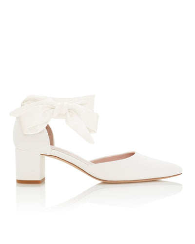 White leather block-heeled shoes with a pointed toe and a decorative bow at the ankle. The image is taken from a side angle, showcasing the shoe against a neutral background. The heel height is approximately 2.5 inches.