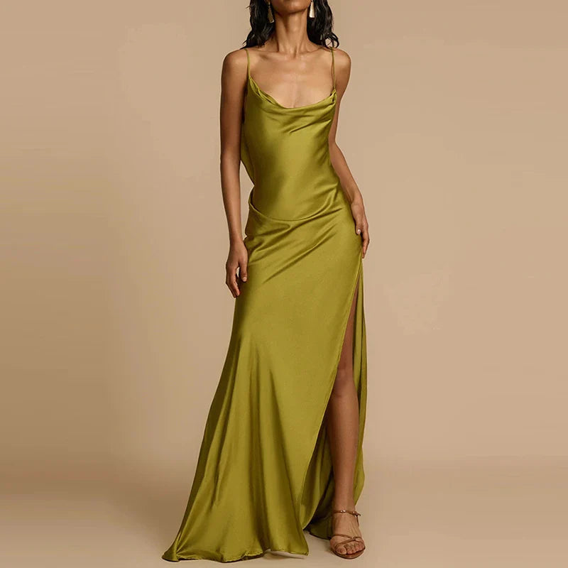 Woman wearing a green evening gown with a slit on a beige background