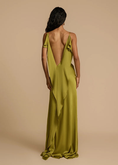 Woman wearing a green evening gown with a deep back on a beige background