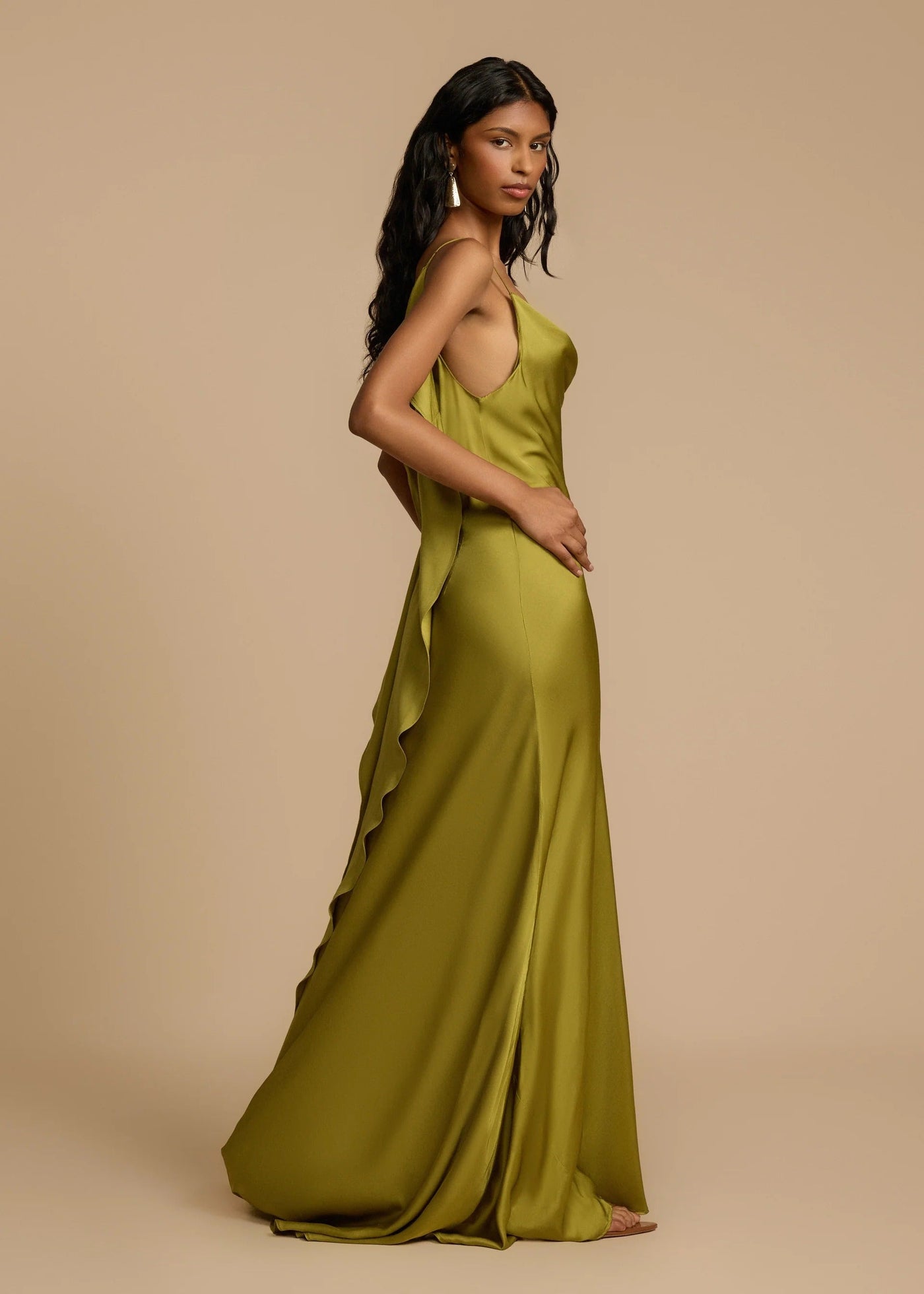 Woman wearing a green evening gown against a beige background