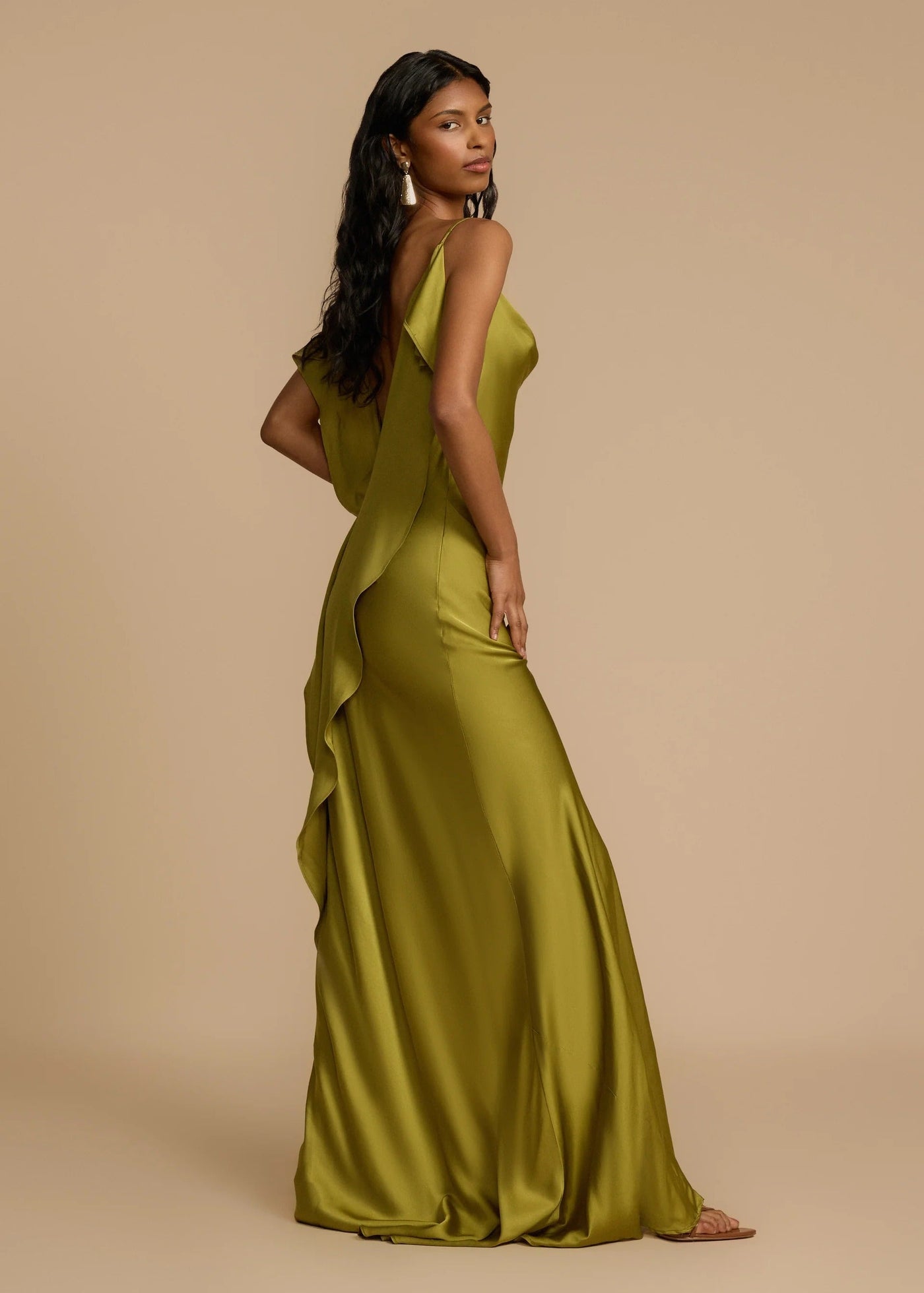 Woman wearing a green evening gown against a beige background