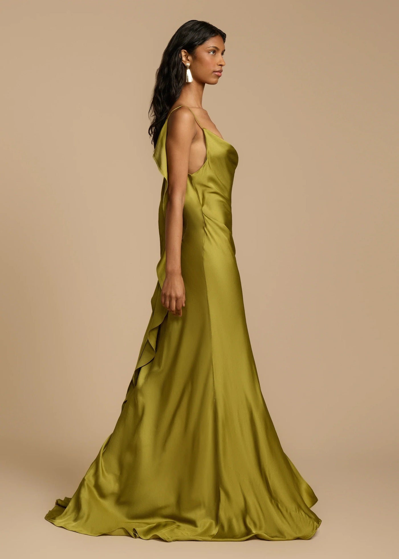 Woman wearing a green satin gown against a beige background
