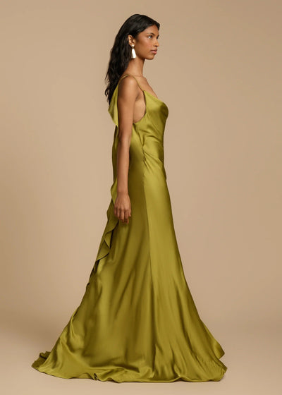 Woman wearing a green satin gown against a beige background
